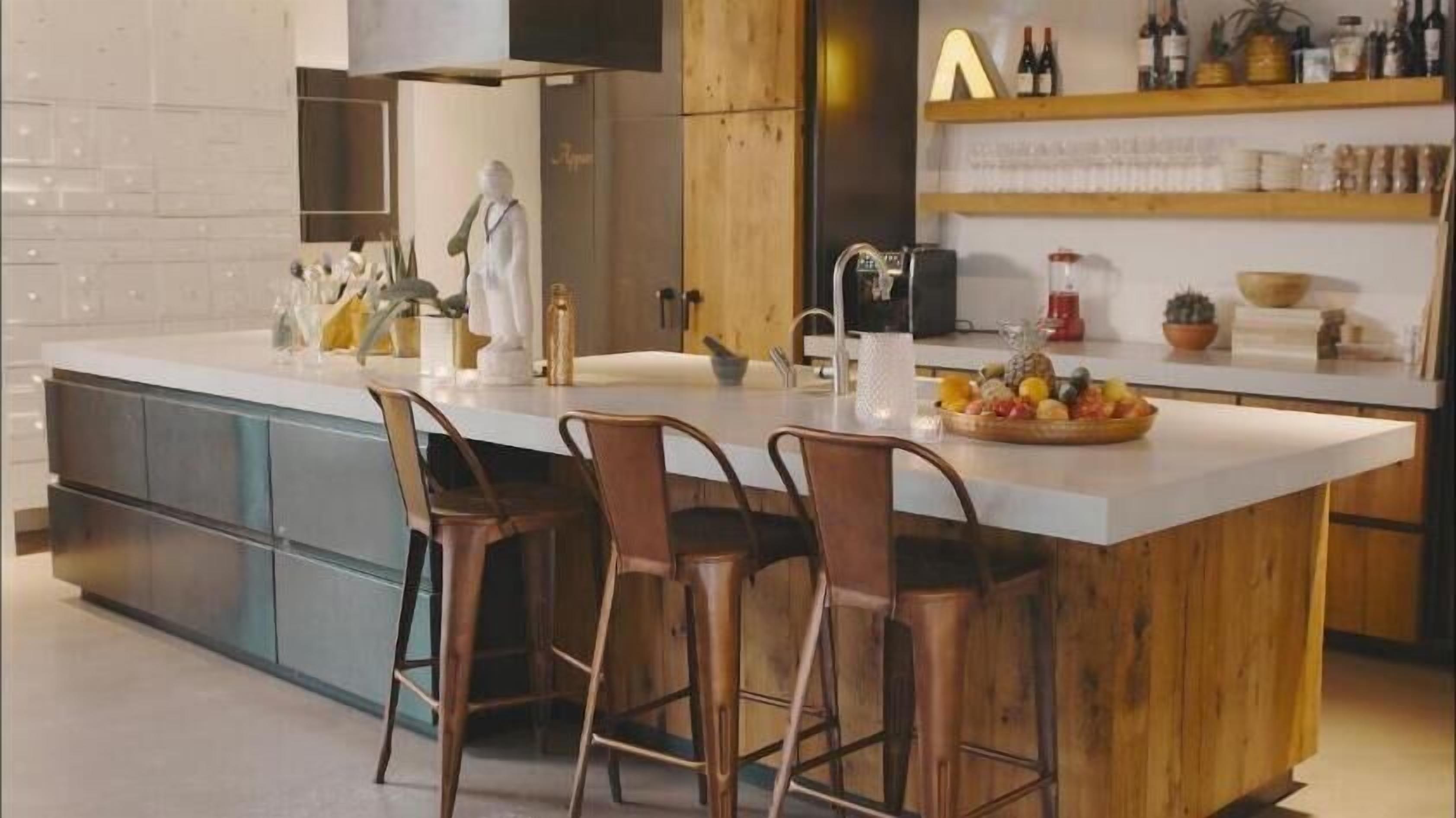 Een moderne keuken met een groot eiland, barstoelen en diverse keukenapparaten en decoratie.