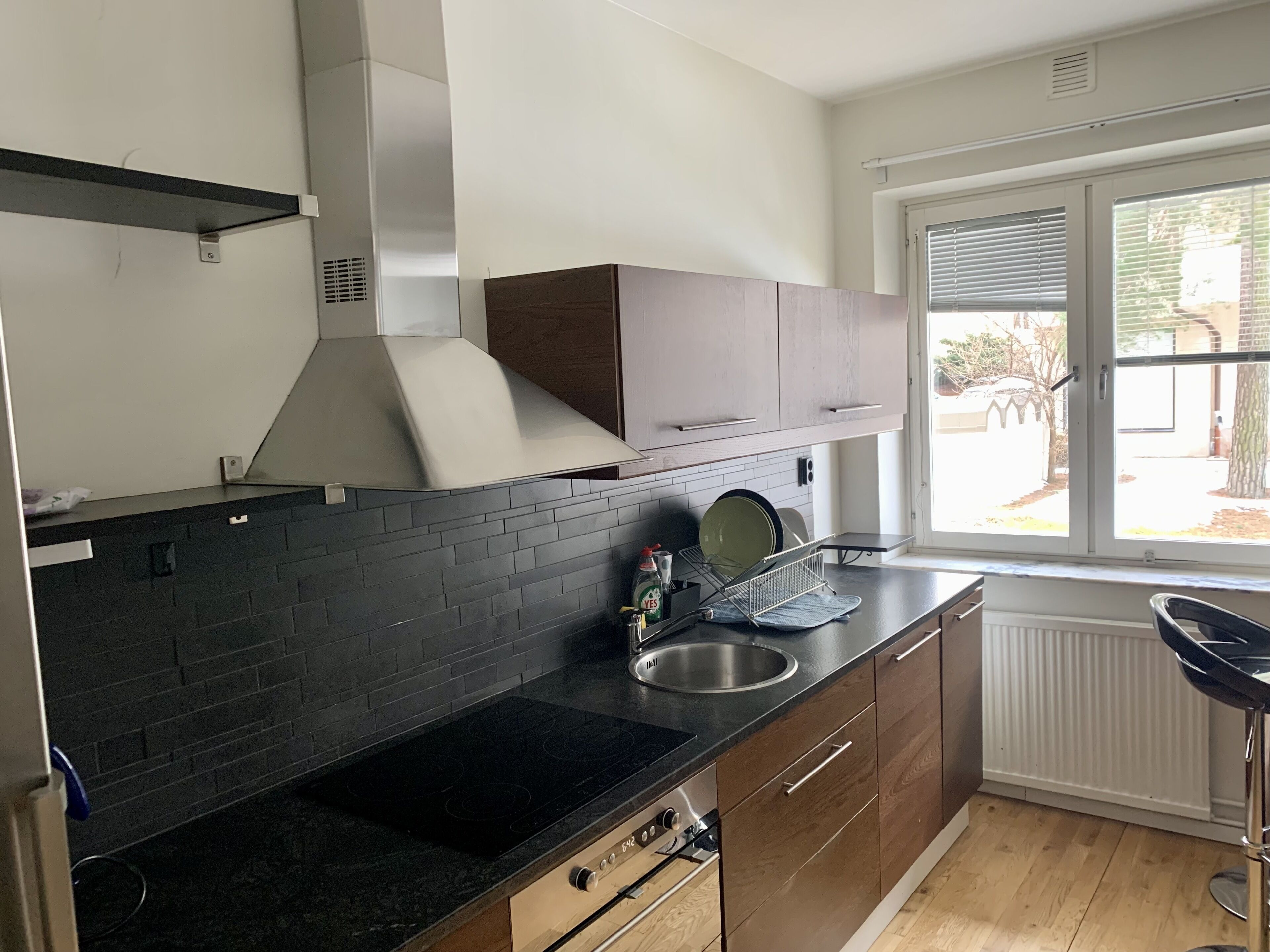 A modern kitchen with a black countertop, stainless steel sink, and wooden cabinets.