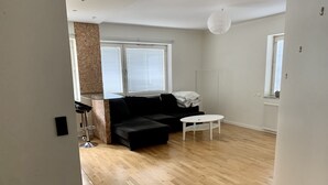 A living room with a black sofa, a white coffee table, and a stone accent wall. - Charming Apartmemt in Stockholm City (Stockholm)