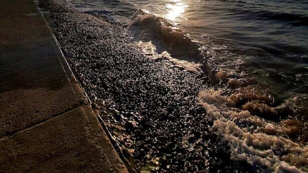 Ein Sonnenuntergang über dem Meer mit einem Betonweg entlang der Küste.