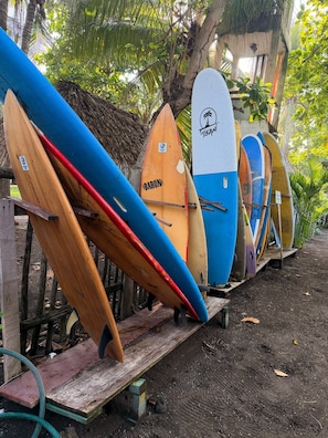 A row of surfboards leaning against a wooden structure in a tropical setting.