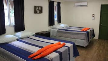 A room with two beds, each with a striped bedspread, a nightstand, and a window with curtains.