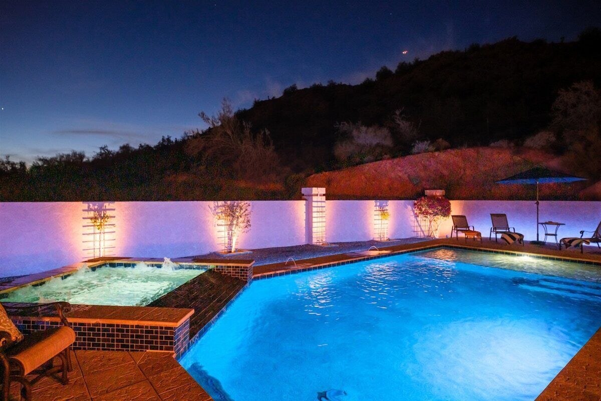 Ein Swimmingpool mit Whirlpool, Liegestühlen und Blick auf eine Hügellandschaft in der Abenddämmerung.