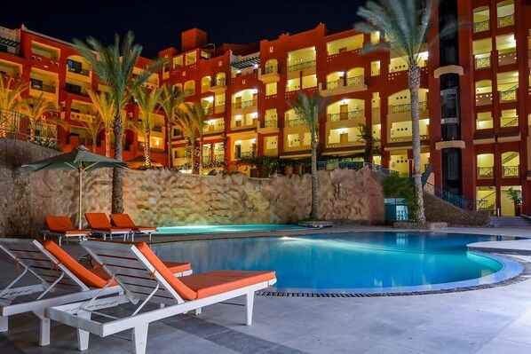 A hotel with a swimming pool, lounge chairs, and palm trees. - Sun & Sea Hotel and Aqua Park - Hurghada (Hurghada)