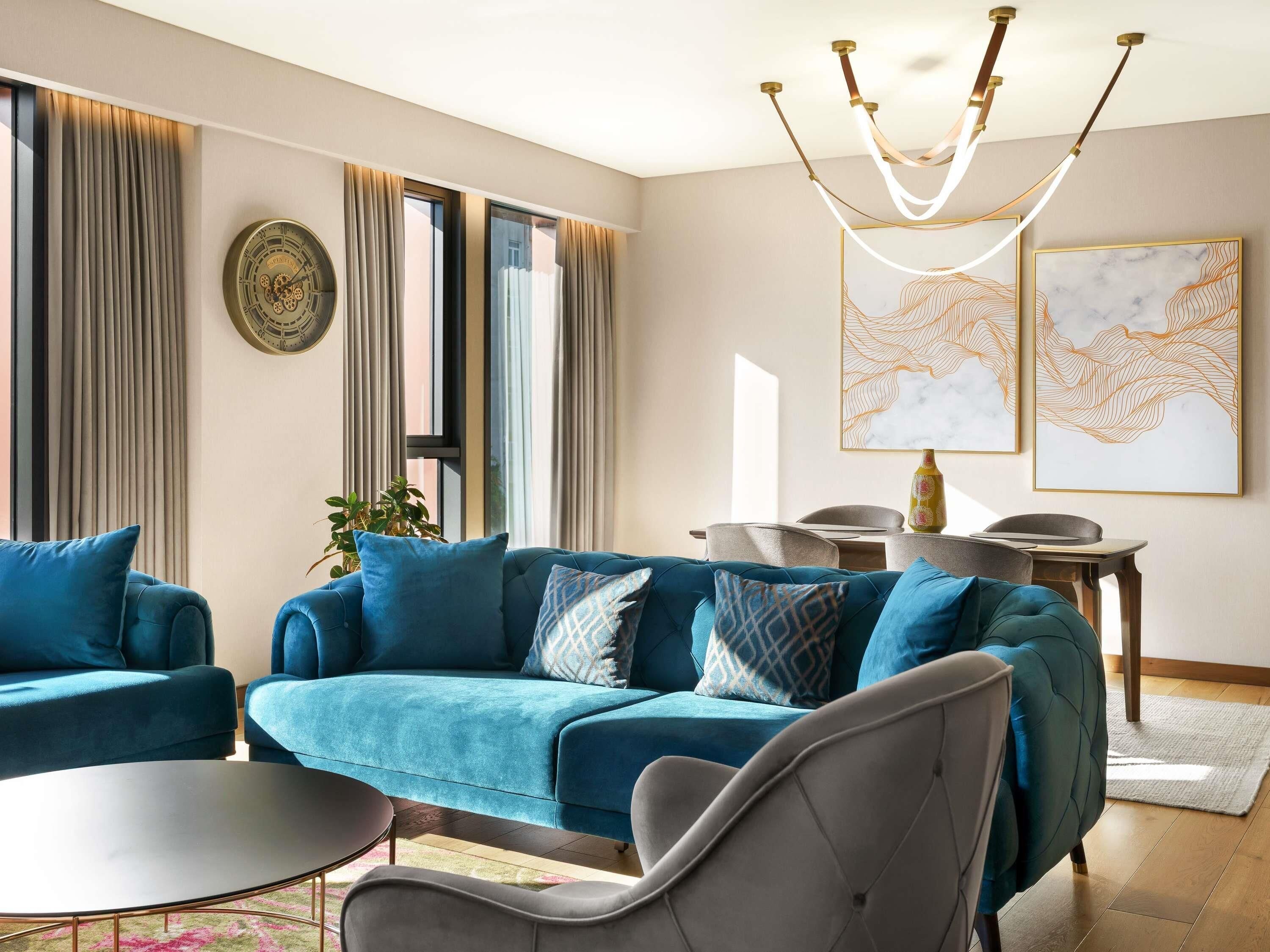 A modern living room with a blue sofa, a round coffee table, and a chandelier.