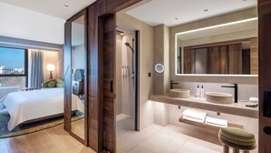 A modern hotel room with a large bed, a bathroom with a vanity, and a view of the city. - Swissôtel Tbilisi (Tbilisi)