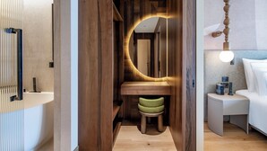 A modern bathroom with a wooden vanity, a round mirror, and a small stool. - Swissôtel Tbilisi (Tbilisi)