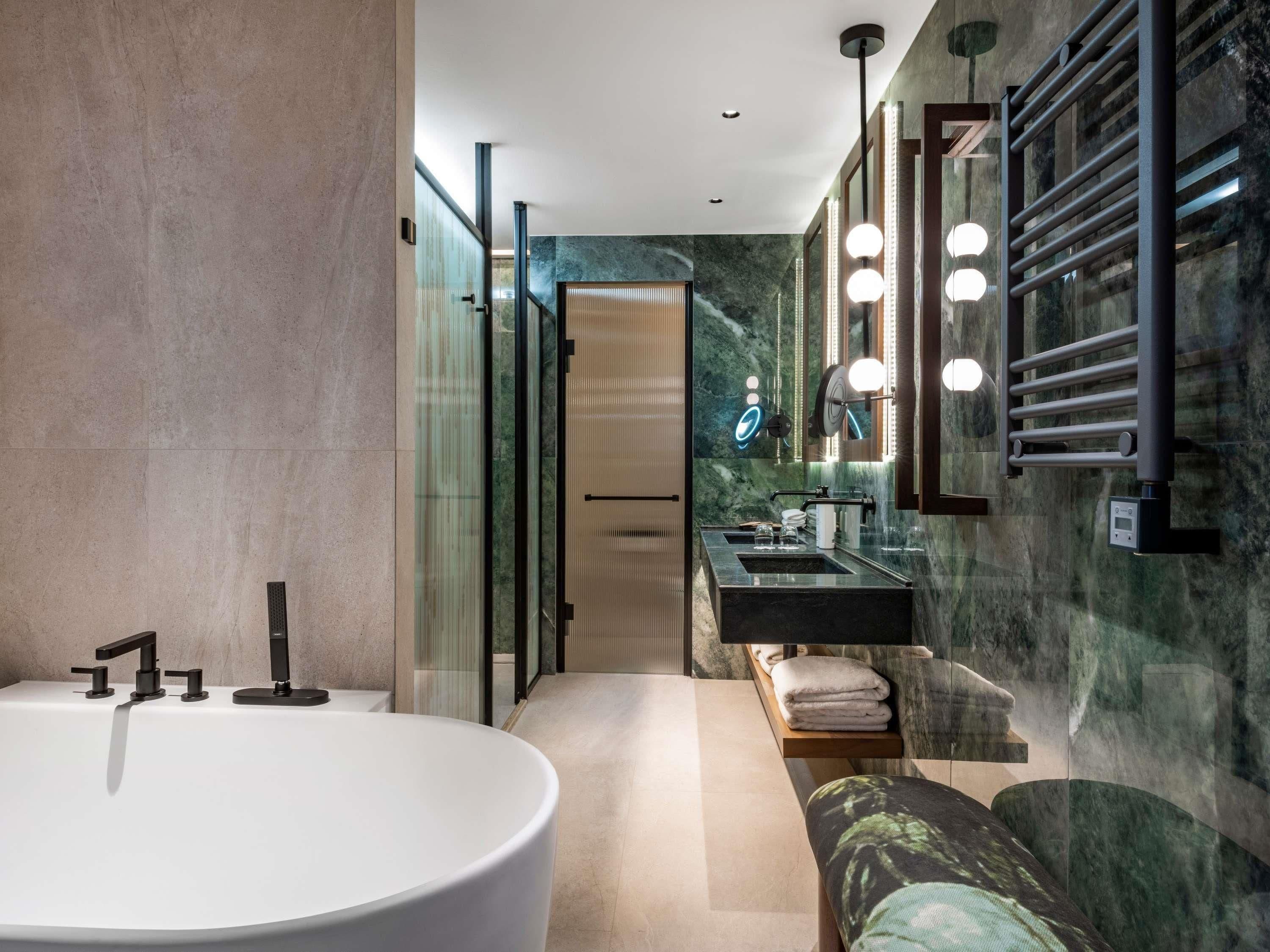 Une salle de bain moderne avec une baignoire sur pieds, un meuble-lavabo et un miroir avec éclairage intégré.