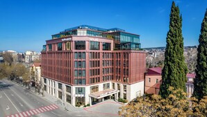 A modern hotel with a red facade, large windows, and a rooftop terrace. - Swissôtel Tbilisi (Tbilisi)