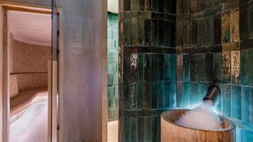 A steam room with a sign, a tiled wall, and a bucket of ice.