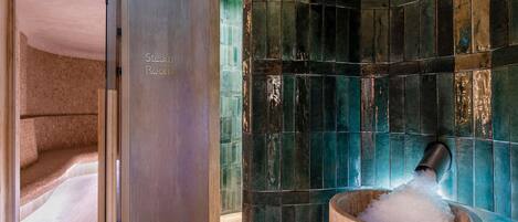 Un baño de vapor con un cartel, una pared de azulejos y un cubo de hielo.