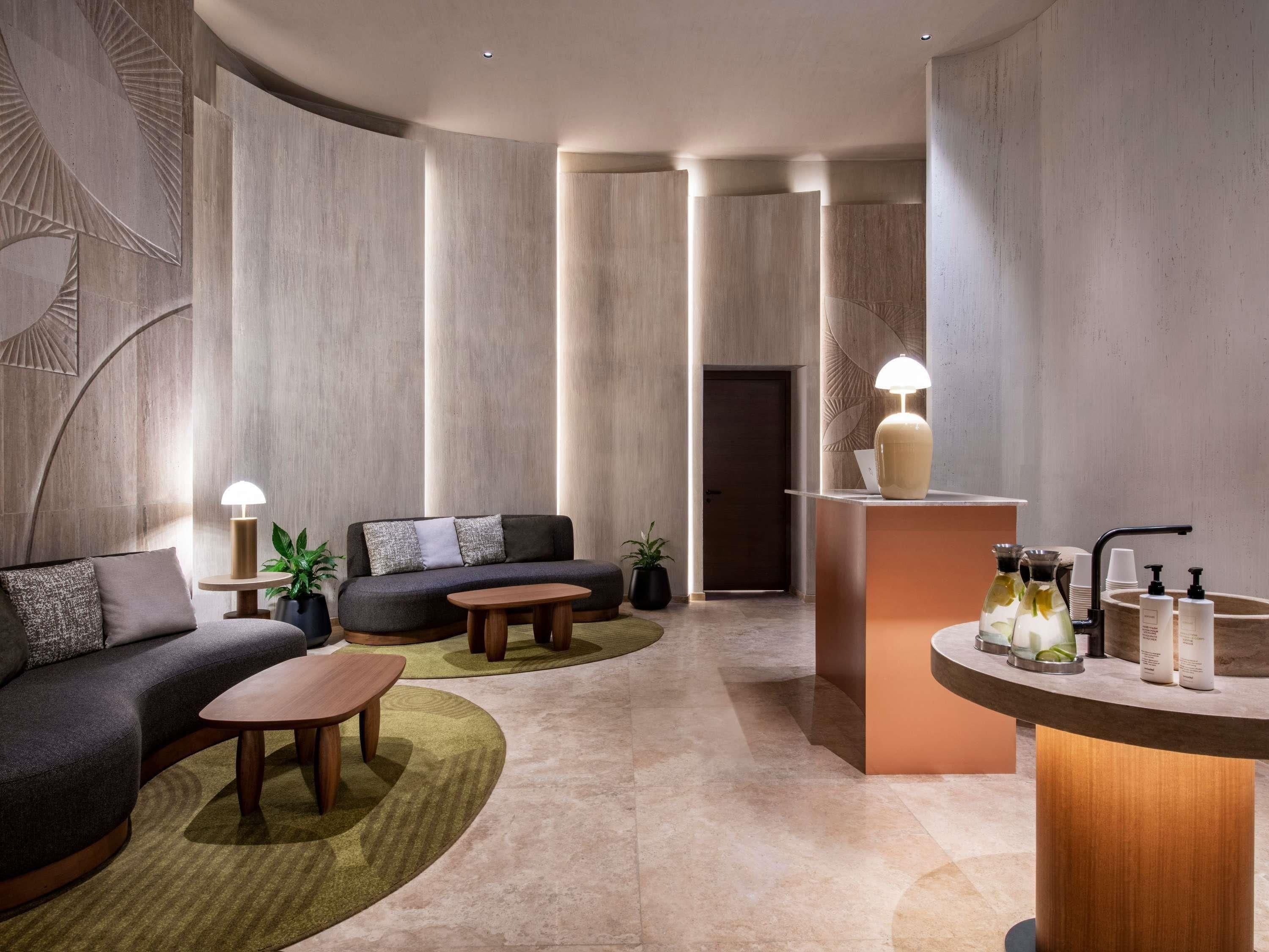 A modern hotel lobby with a sofa, coffee table, and a reception desk with amenities.