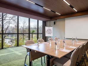 Une salle de conférence équipée d’une grande table, de chaises, de bouteilles d’eau et d’un écran de présentation.