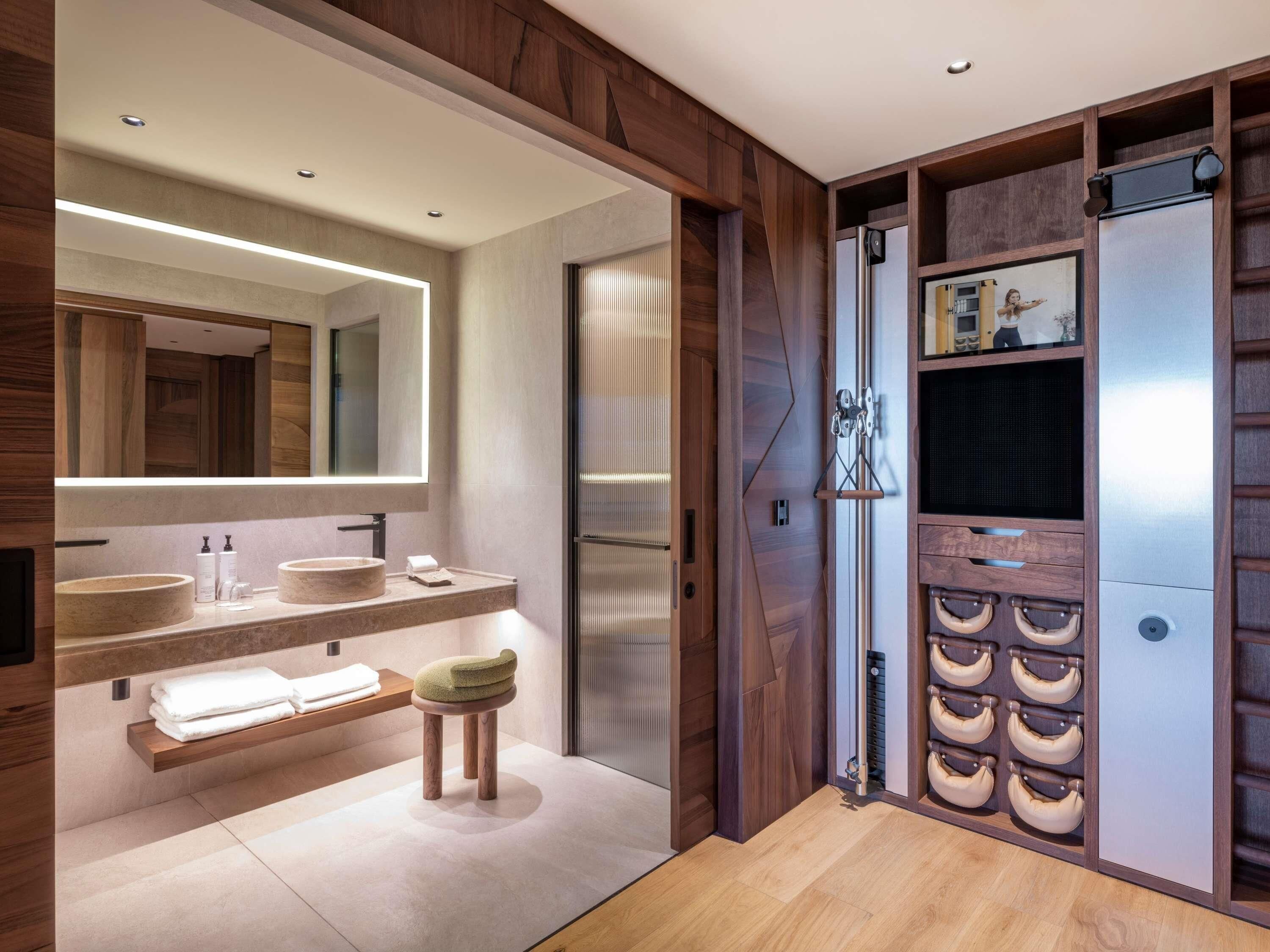 A modern bathroom with wooden accents, a large mirror, two sinks, a vanity, and a towel rack.