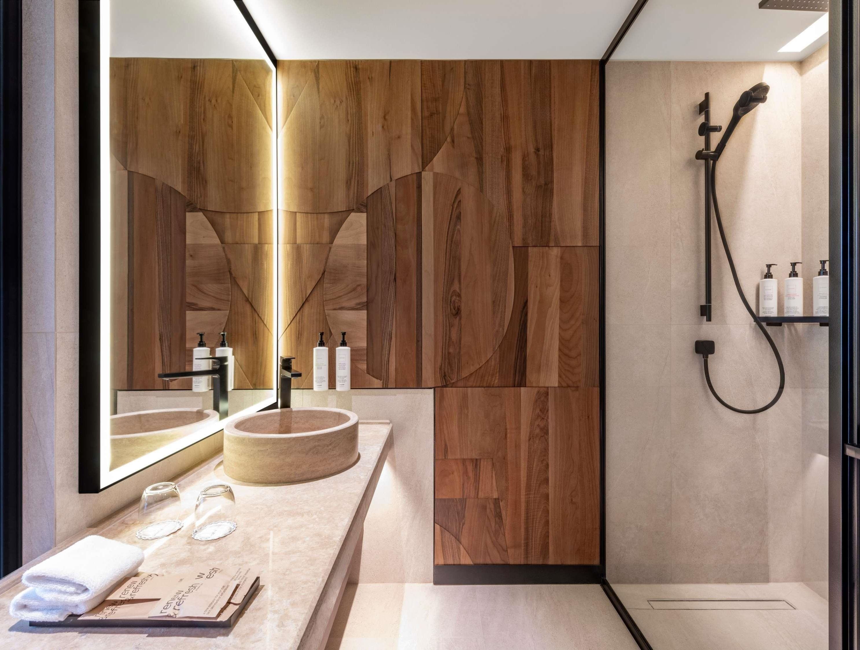 Une salle de bain moderne avec un meuble-lavabo en bois, un grand miroir, un lavabo rond et un espace douche.