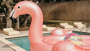 Une piscine avec des bouées en forme de flamants roses et des chaises longues.
