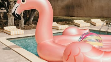 Piscina com boias de flâmigo e espreguiçadeiras.