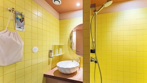 Une salle de bain avec des carreaux jaunes, un lavabo blanc et une douche.