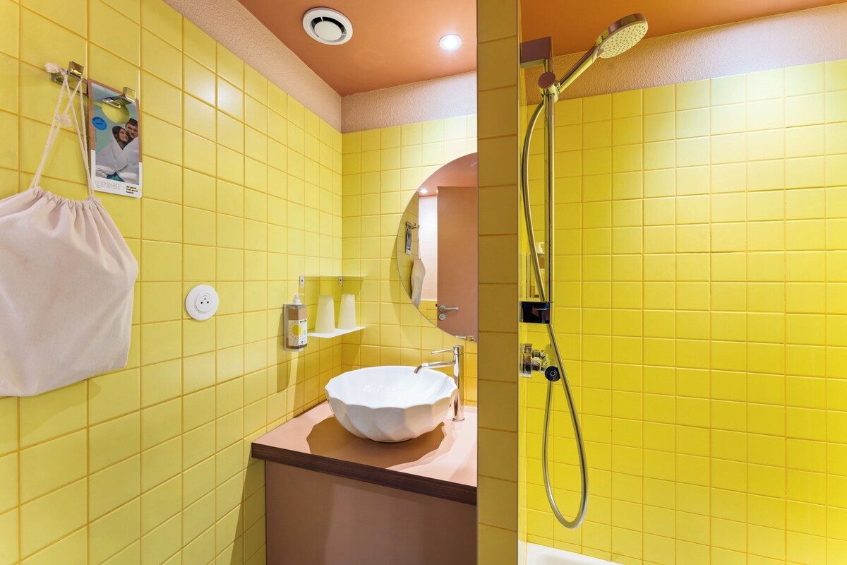 Ein Badezimmer mit gelben Fliesen, einem weißen Waschbecken und einer Dusche.