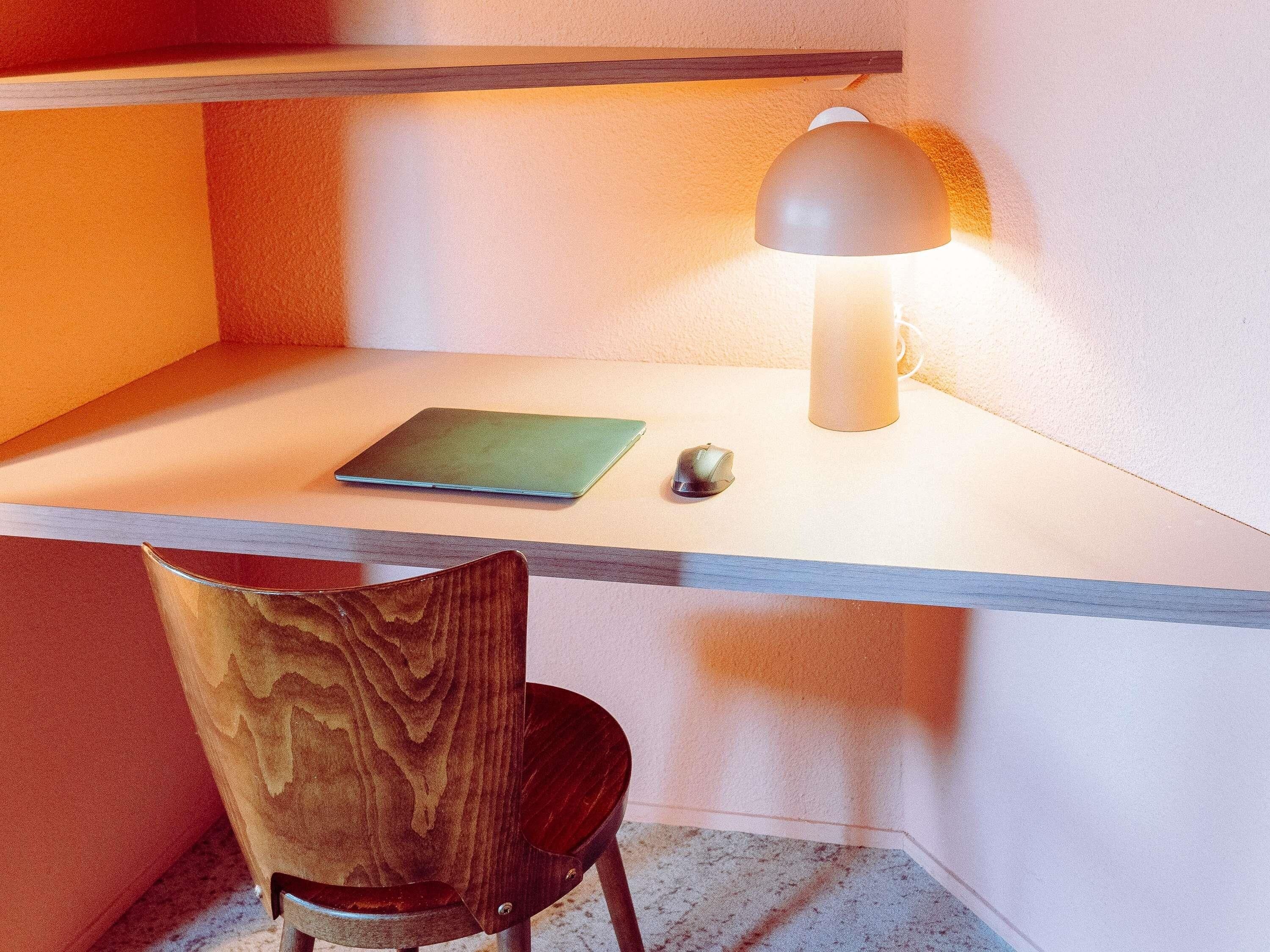 Un bureau avec un ordinateur portable, une souris et une lampe.