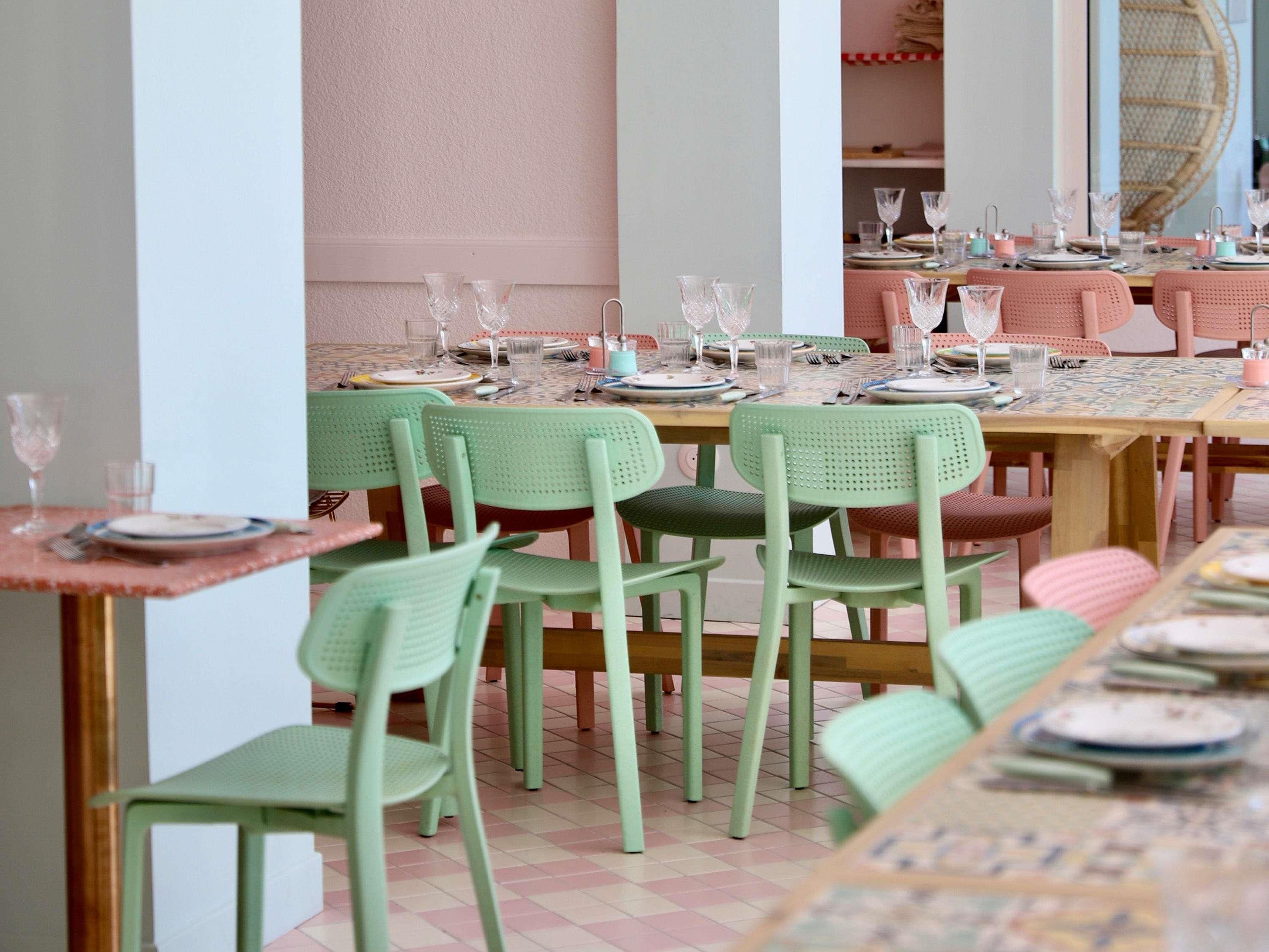 Un espace repas avec des tables dressées pour plusieurs personnes, des chaises et de la vaisselle.