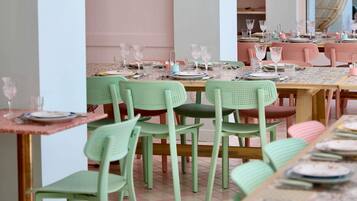 Un espace repas avec des tables dressées pour plusieurs personnes, des chaises et de la vaisselle.