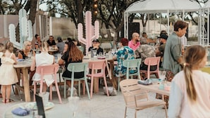 Un espace extérieur aménagé pour les repas, avec des tables et des chaises, un gazebo blanc et des cactus décoratifs.
