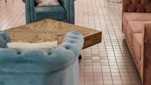 Une pièce avec un fauteuil bleu, une table basse en bois et un canapé rose.