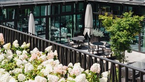 A rooftop terrace with outdoor seating, glass walls, and a view of the city. - Domaine de la Reine Margot Paris-Issy - MGallery Collection (Issy-les-Moulineaux)