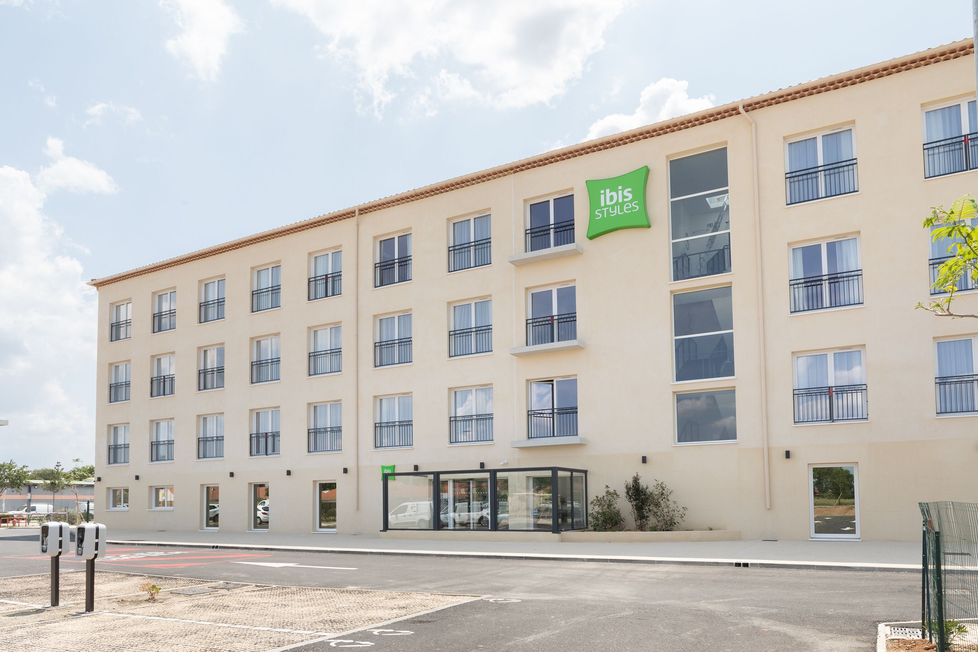 Un hôtel à plusieurs étages, doté d’une façade sobre, de grandes fenêtres et d’une enseigne verte indiquant qu’il s’agit d’un hôtel ibis.