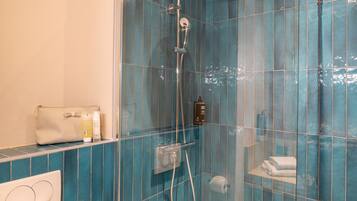 Une salle de bain avec une douche à parois de verre, un porte-serviettes et des articles de toilette rangés sur une étagère.