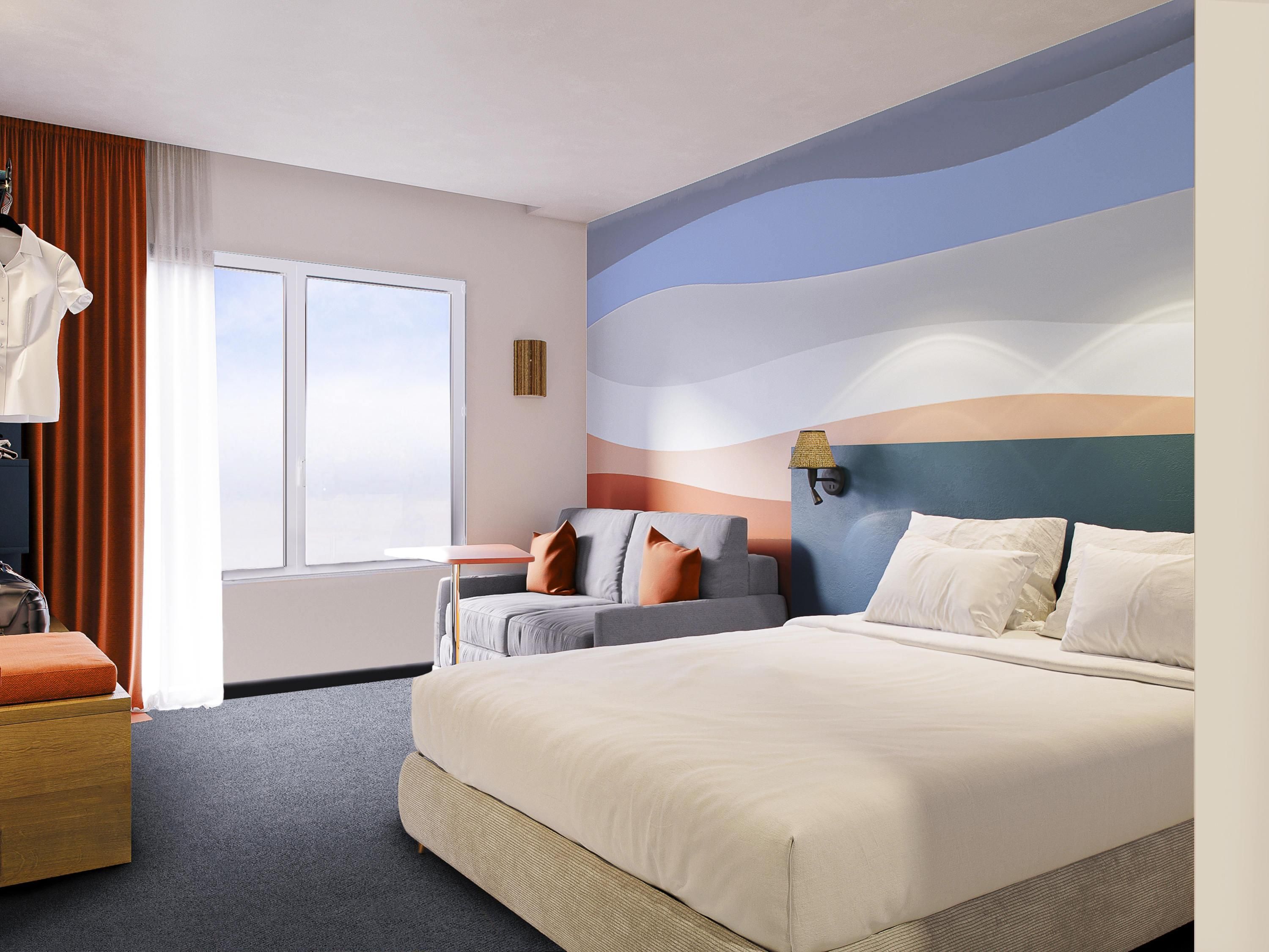 A hotel room with a large bed, a sofa, a desk, and a window with curtains.