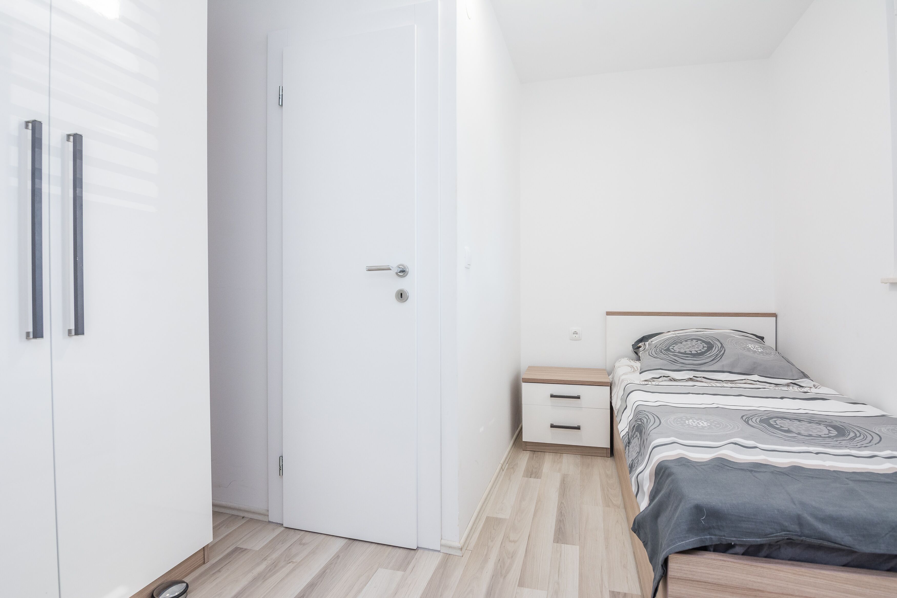 Ein Schlafzimmer mit Bett, Nachttisch, Kleiderschrank und Tür.