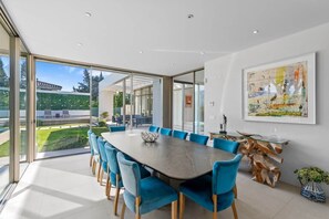A modern dining room with a large table and blue chairs, large windows, and a painting on the wall. - RDR234 - Amazing modern villa located minutes from beach (Marbella)