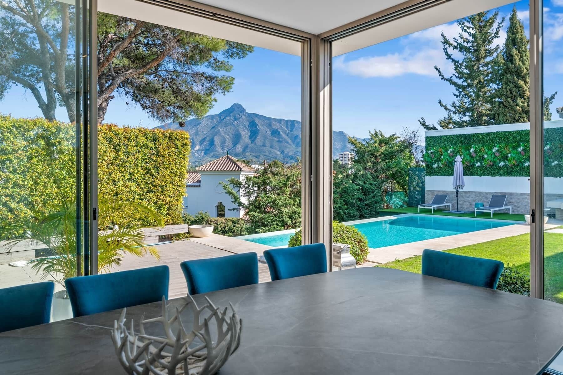 Un espace de restauration moderne offrant une vue sur une piscine et des montagnes.