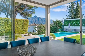 Un espace de restauration moderne offrant une vue sur une piscine et des montagnes.
