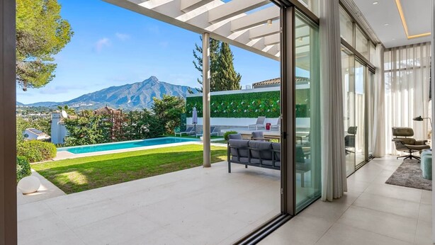 A modern house with a glass door leading to a patio with a pool, outdoor furniture, and a view of mountains. - RDR234 - Amazing modern villa located minutes from beach (Marbella)
