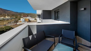 A balcony with a glass table and two chairs, overlooking a cityscape with buildings and mountains. - RDR274 - NEW 3 bedroom Apt with pool + near beach (Estepona)