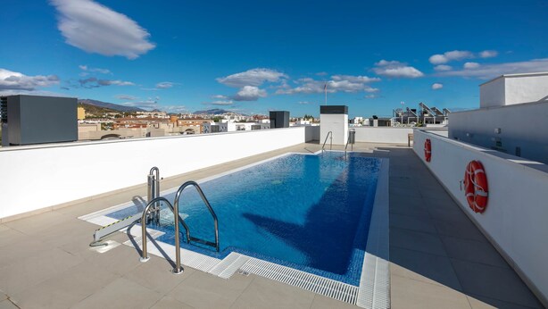 A rooftop swimming pool with a clear view of the cityscape in the background. - RDR274 - NEW 3 bedroom Apt with pool + near beach (Estepona)