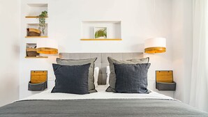 Une chambre moderne avec un grand lit, deux tables de chevet, une tête de lit, des étagères murales et une lampe suspendue.