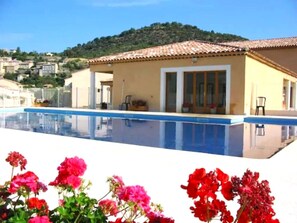 A poolside view of a building with a tiled roof and a clear blue sky.
