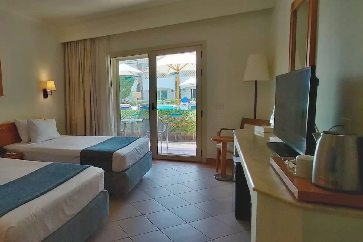 Ein Hotelzimmer mit zwei Betten, einem Fernseher und Blick ins Freie.