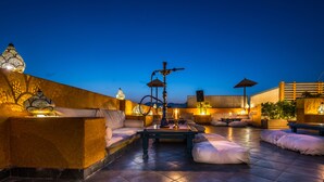 A rooftop terrace with seating, a coffee table, and a hookah. - Camel Dive Club & Boutique Hotel (Sharm El Sheikh)