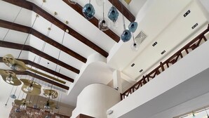 A modern hotel lobby with a high ceiling, a stone wall, and a sign for Camel Dive Club & Hotel. - Camel Dive Club & Boutique Hotel (Sharm El Sheikh)