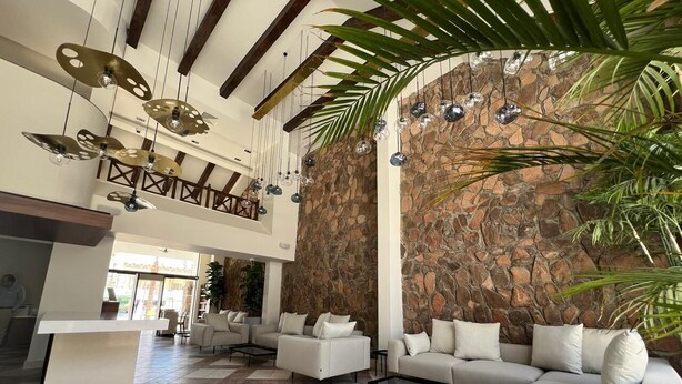 A spacious lobby with a high ceiling, stone wall, and modern furniture. - Camel Dive Club & Boutique Hotel (Sharm El Sheikh)
