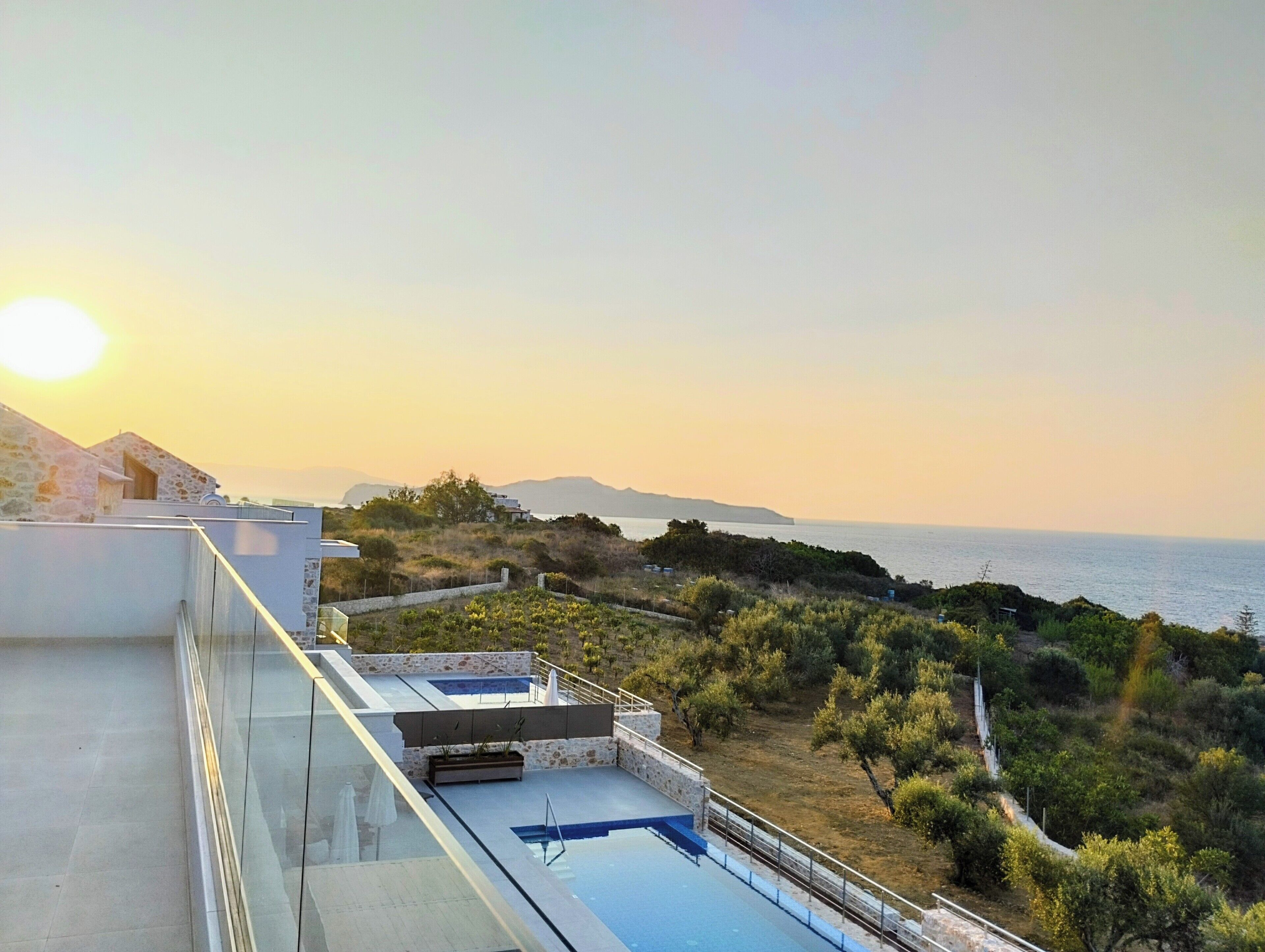 A rooftop pool with a view of the sea and distant mountains.
