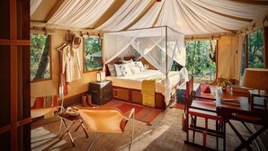 Ein Zelt mit einem Bett, einem Tisch, Stühlen und Blick ins Freie.