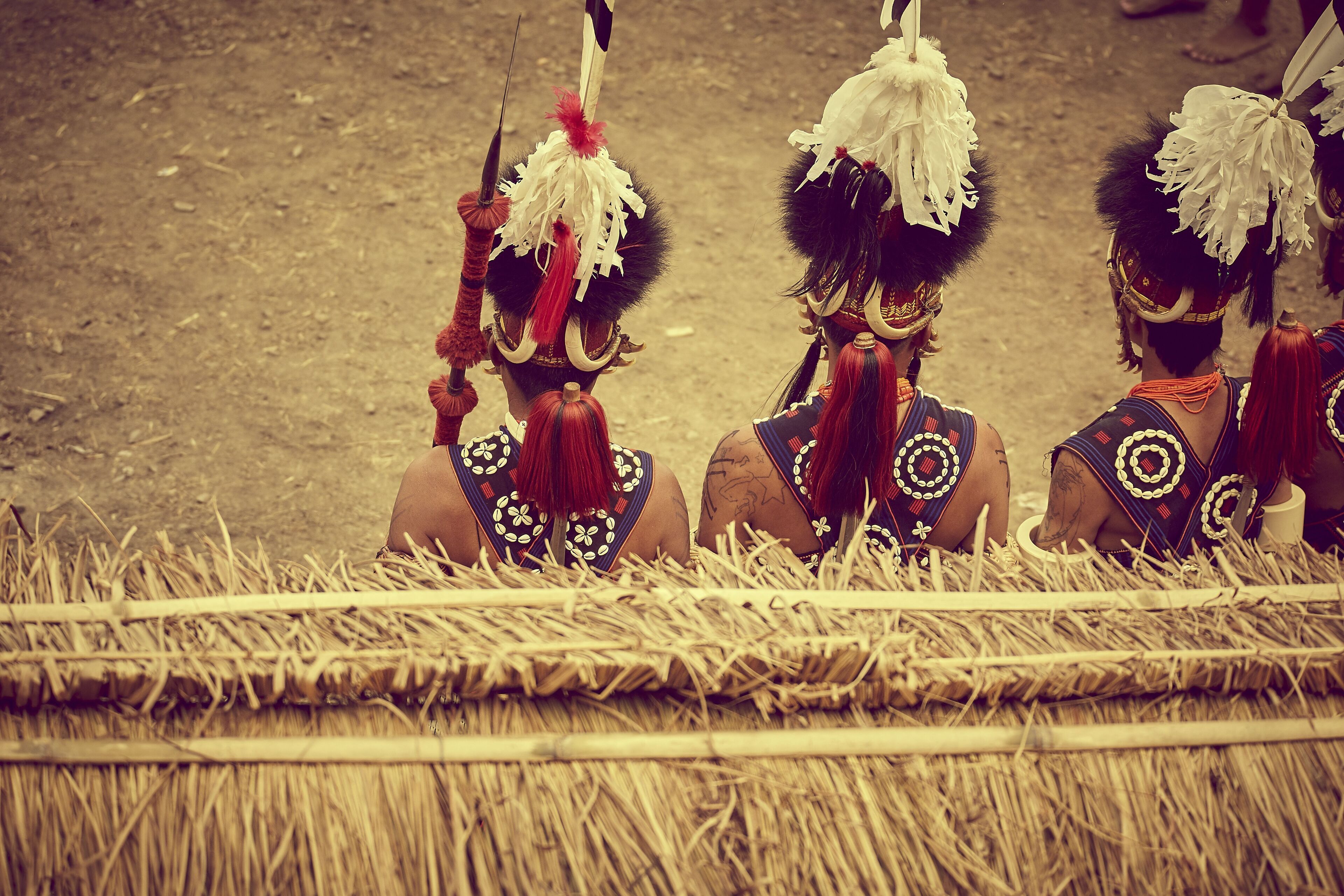 A group of individuals in traditional attire sitting on straw.