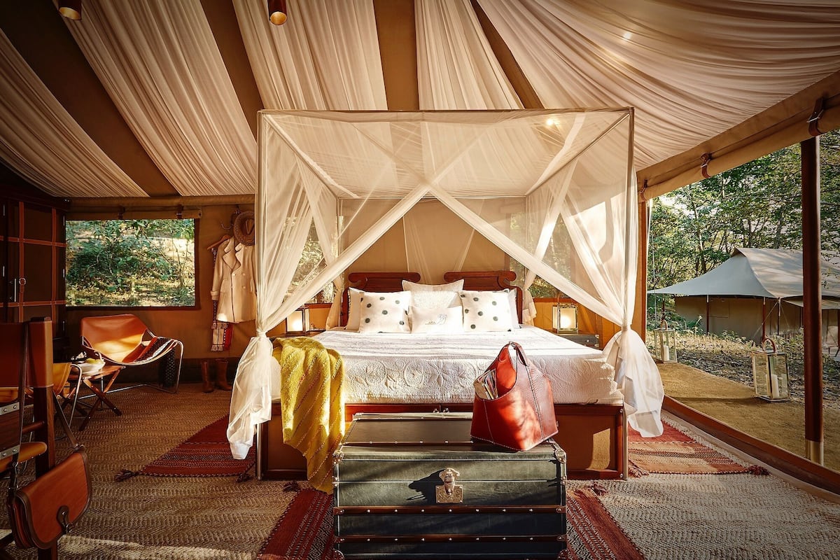 A spacious bedroom with a canopy bed, a wooden headboard, and a large window offering a view of the outdoors.