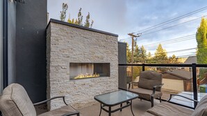 An outdoor patio with stone walls, a fire feature, and outdoor furniture. - Luxury Home in Quiet Neighborhood near Downtown with Fast Wi-F & 3 Workspaces (Calgary)